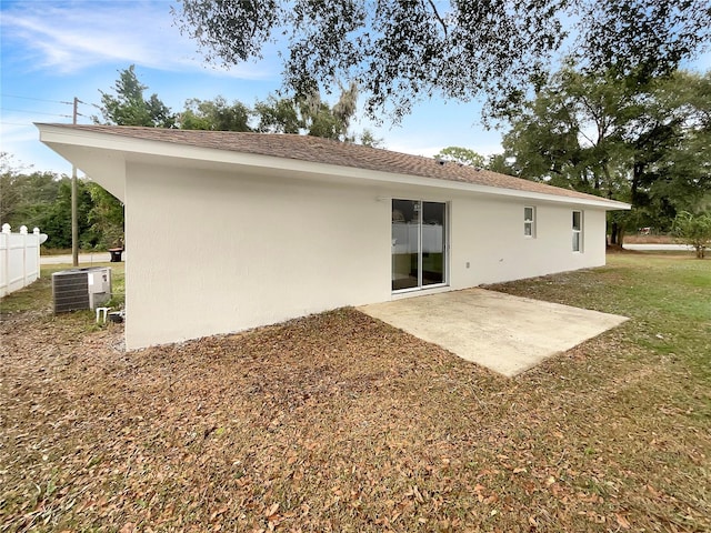 rear view of house featuring central AC unit, a patio area, and a lawn