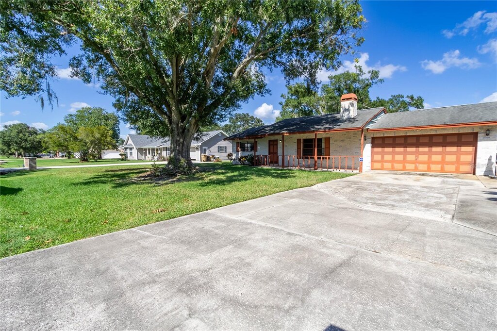 single story home with a garage, a porch, and a front yard