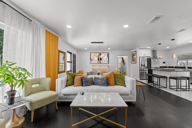 living room with wood-type flooring, a notable chandelier, and sink