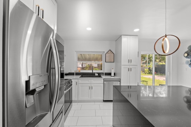 kitchen featuring pendant lighting, sink, light tile patterned floors, appliances with stainless steel finishes, and white cabinetry