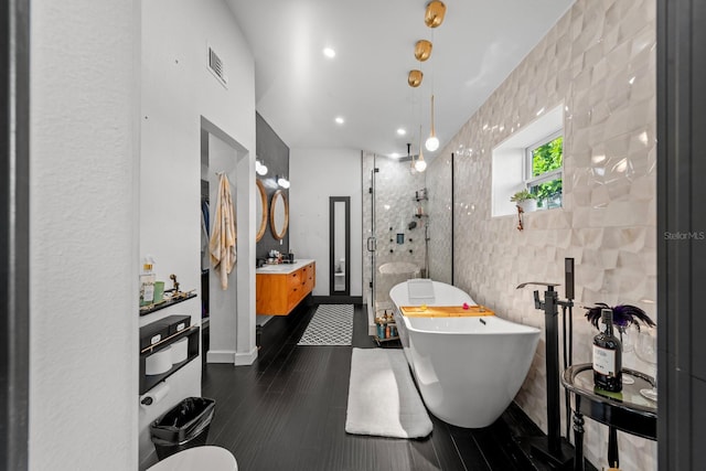 bathroom with vanity, separate shower and tub, wood-type flooring, and tile walls