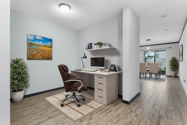 office area with light hardwood / wood-style floors and a textured ceiling