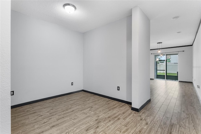 spare room with a textured ceiling and light hardwood / wood-style floors