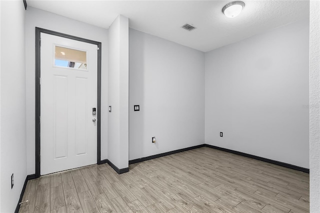 entryway with a textured ceiling and light hardwood / wood-style flooring