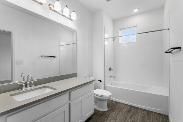 full bathroom featuring hardwood / wood-style floors, vanity, toilet, and tiled shower / bath