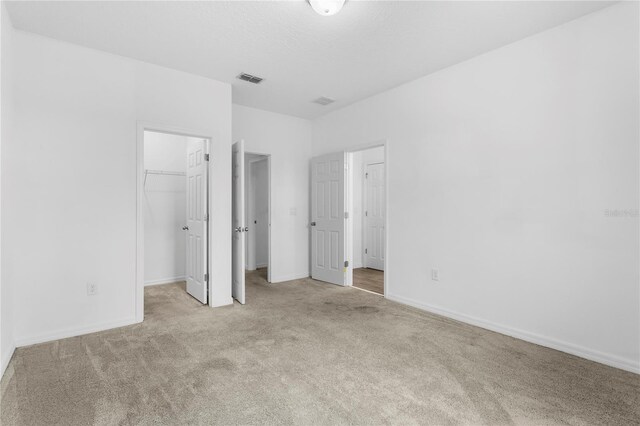 unfurnished bedroom featuring light carpet, a spacious closet, and a closet