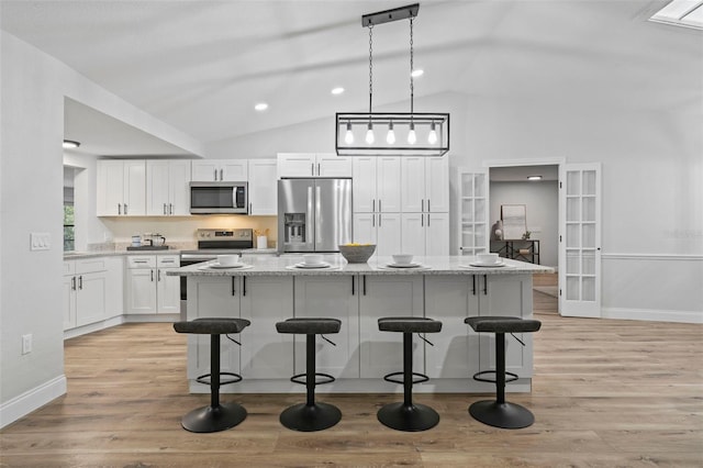 5016 Dorman Rd, Lakeland, FL 33813 - kitchen featuring stainless steel appliances, white cabinets, a breakfast bar, light stone countertops, and high vaulted ceiling