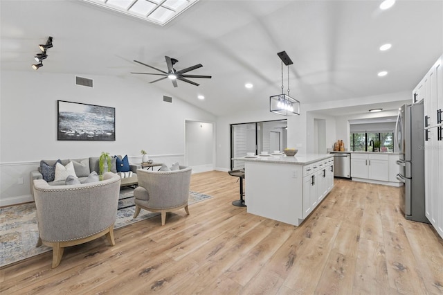 kitchen with white cabinets, decorative light fixtures, stainless steel appliances, and vaulted ceiling