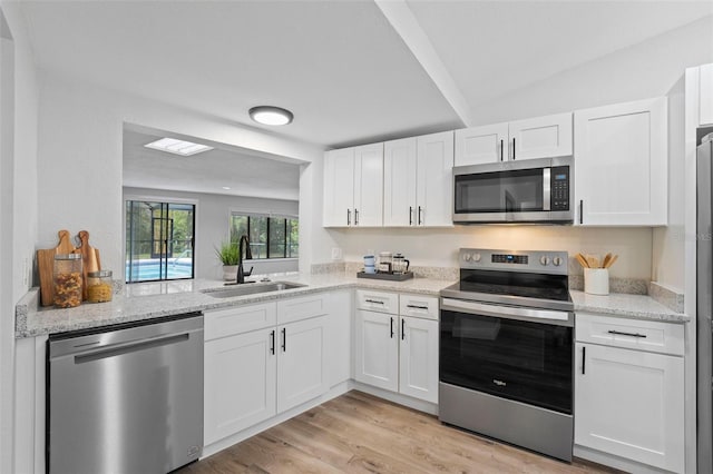 5016 Dorman Rd, Lakeland, FL 33813 - kitchen with appliances with stainless steel finishes, white cabinets, light wood-type flooring, and light stone counters