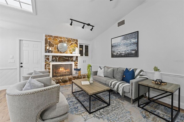 5016 Dorman Rd, Lakeland, FL 33813 - living room featuring track lighting, a fireplace, a wainscoted wall, vaulted ceiling, and wood finished floors