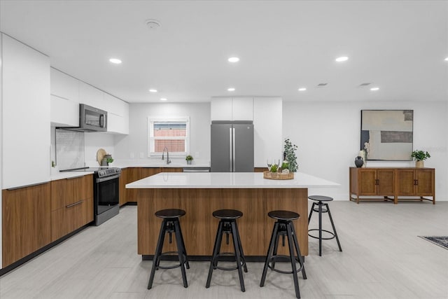 kitchen featuring a kitchen breakfast bar, a center island, white cabinets, and stainless steel appliances