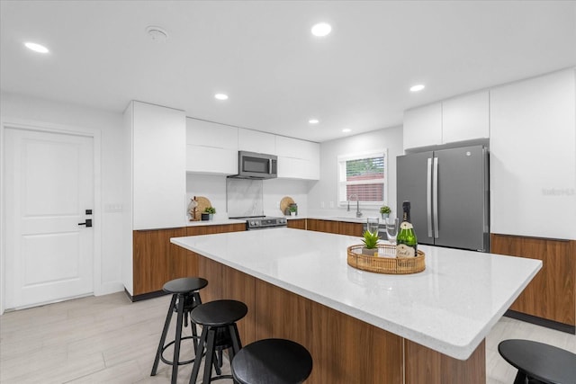 kitchen with light hardwood / wood-style floors, a center island, white cabinetry, and appliances with stainless steel finishes