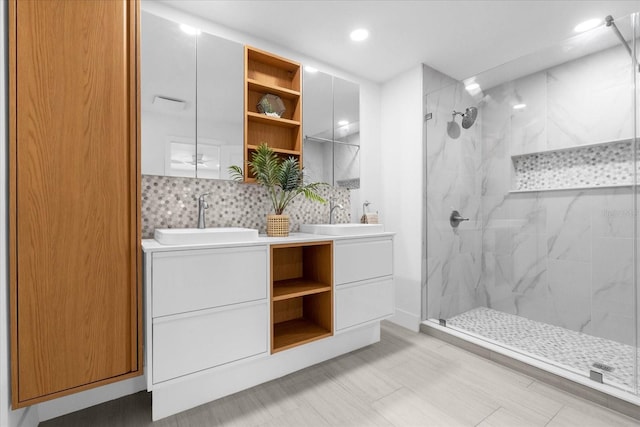 bathroom with vanity, a tile shower, and backsplash