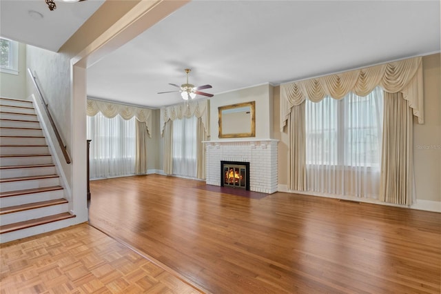 unfurnished living room with ceiling fan, crown molding, a fireplace, and light hardwood / wood-style flooring