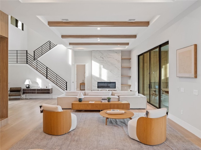 living room with light wood-type flooring, a fireplace, and beam ceiling