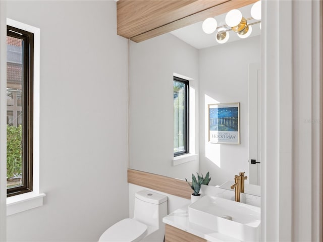 bathroom with toilet, vanity, and a notable chandelier