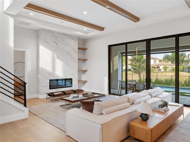 living room with light hardwood / wood-style floors, built in features, and beam ceiling