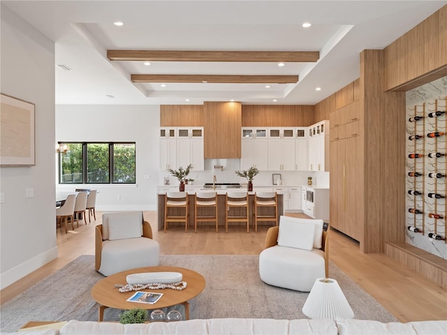 living room featuring beam ceiling, wooden walls, and light hardwood / wood-style floors