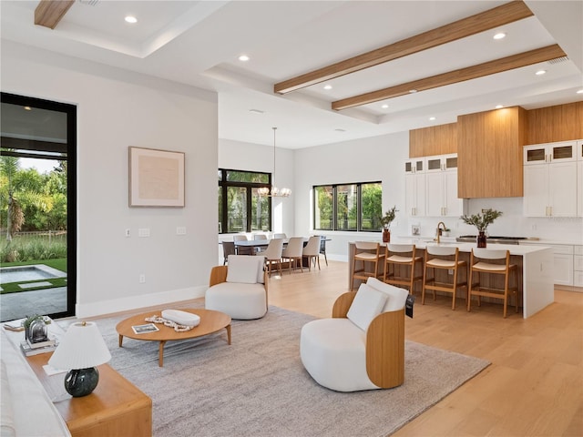 living room with a high ceiling, an inviting chandelier, and light hardwood / wood-style floors