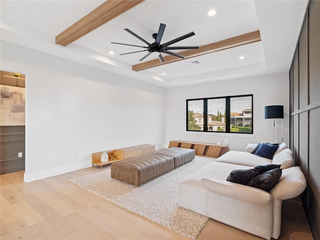 living room featuring ceiling fan, light hardwood / wood-style flooring, a raised ceiling, and beamed ceiling