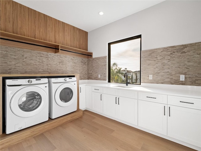 laundry area with washing machine and dryer, cabinets, light wood-type flooring, and sink