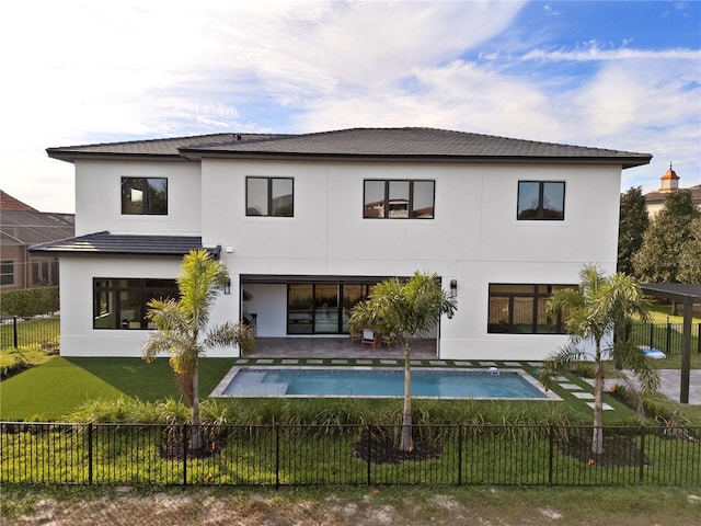 rear view of property featuring a fenced in pool