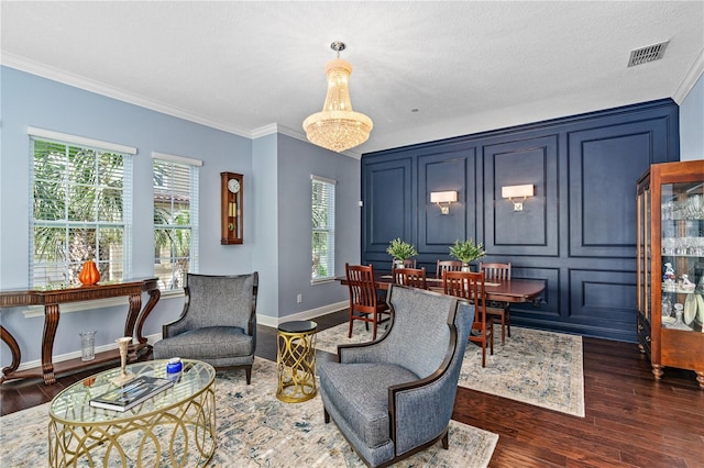 living area with a textured ceiling, dark hardwood / wood-style floors, crown molding, and a chandelier