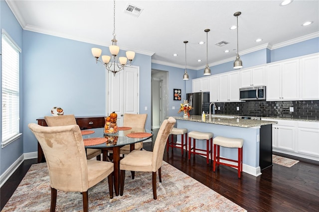 dining space with an inviting chandelier, crown molding, dark wood-type flooring, and sink