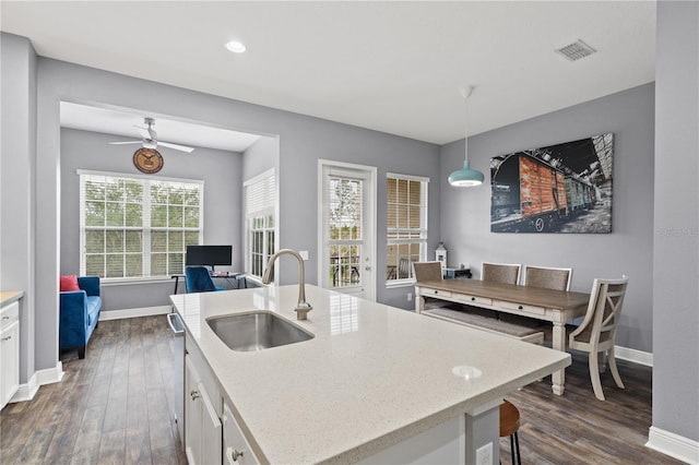 kitchen featuring baseboards, visible vents, dark wood finished floors, white cabinetry, and a sink