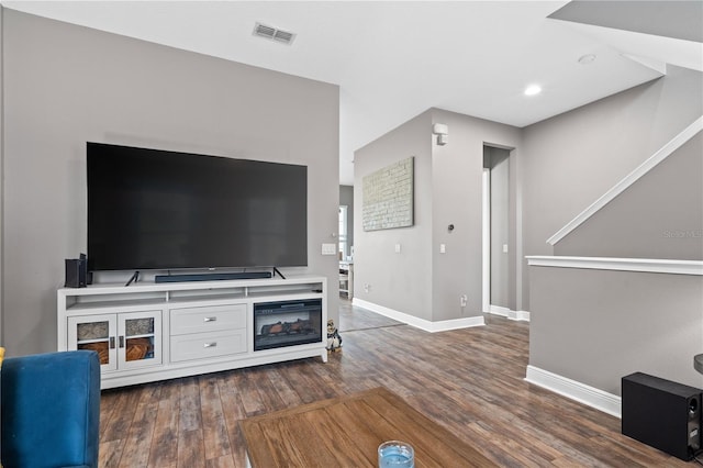 living room with dark wood-type flooring, visible vents, and baseboards