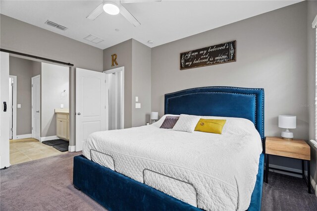 bedroom with a barn door, visible vents, baseboards, ceiling fan, and carpet