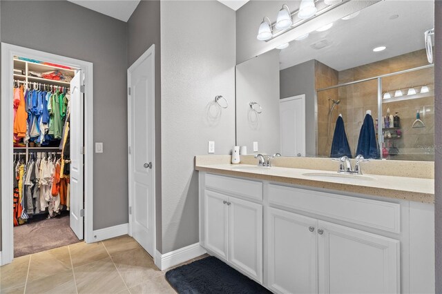 bathroom featuring double vanity, a stall shower, tile patterned floors, a spacious closet, and a sink