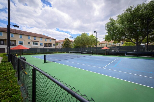 view of tennis court featuring fence and a residential view