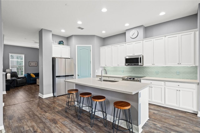 kitchen with stainless steel appliances, dark wood-type flooring, a sink, and a kitchen breakfast bar