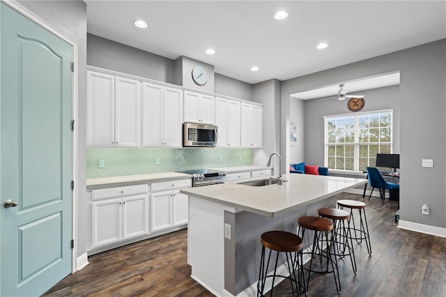 kitchen featuring stainless steel appliances, a sink, backsplash, and dark wood-style floors