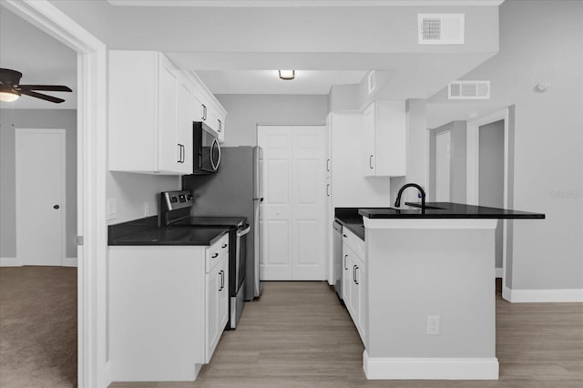 kitchen featuring kitchen peninsula, ceiling fan, light wood-type flooring, appliances with stainless steel finishes, and white cabinetry