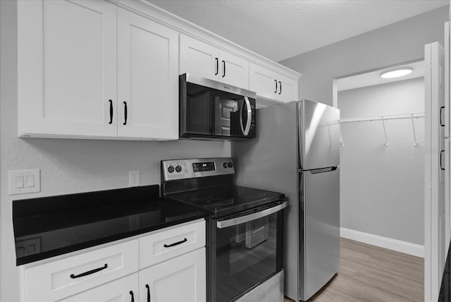 kitchen featuring white cabinets, stainless steel appliances, a textured ceiling, and light hardwood / wood-style floors