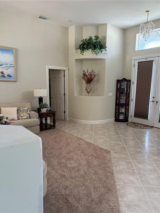 foyer with light colored carpet, french doors, a high ceiling, and a chandelier