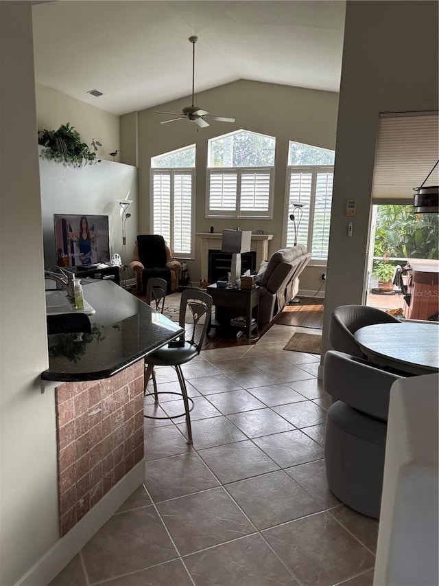 tiled living room with ceiling fan and vaulted ceiling