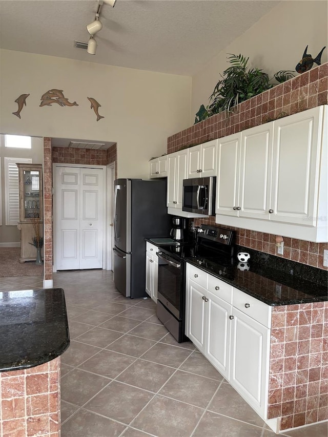 kitchen featuring tile patterned floors, white cabinetry, appliances with stainless steel finishes, and dark stone counters