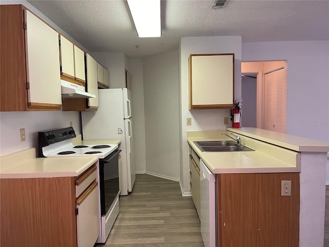 kitchen featuring kitchen peninsula, light wood-type flooring, white appliances, and a textured ceiling