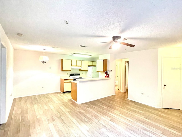 kitchen with electric range oven, light hardwood / wood-style flooring, white refrigerator, kitchen peninsula, and a textured ceiling