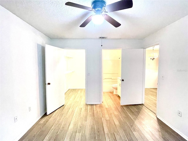 unfurnished bedroom featuring connected bathroom, ceiling fan, light hardwood / wood-style flooring, and a textured ceiling