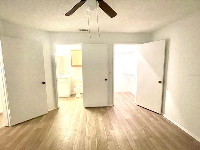 interior space featuring ensuite bath, ceiling fan, light hardwood / wood-style floors, and a textured ceiling