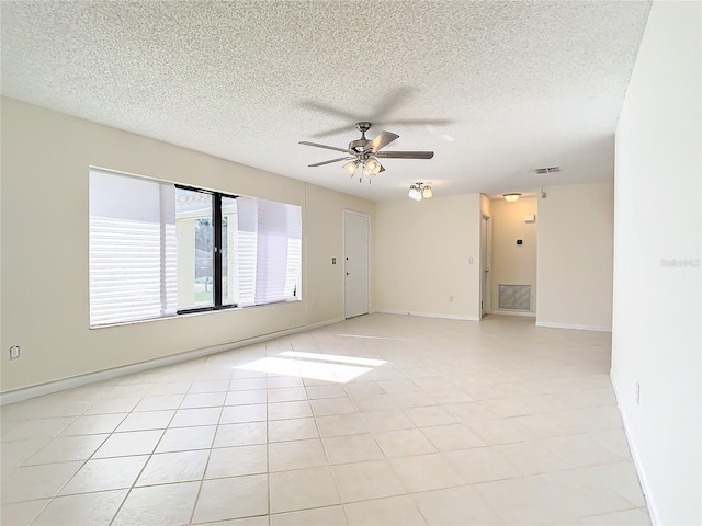 empty room with ceiling fan, light tile patterned floors, and a textured ceiling