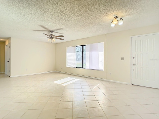 tiled empty room with ceiling fan and a textured ceiling