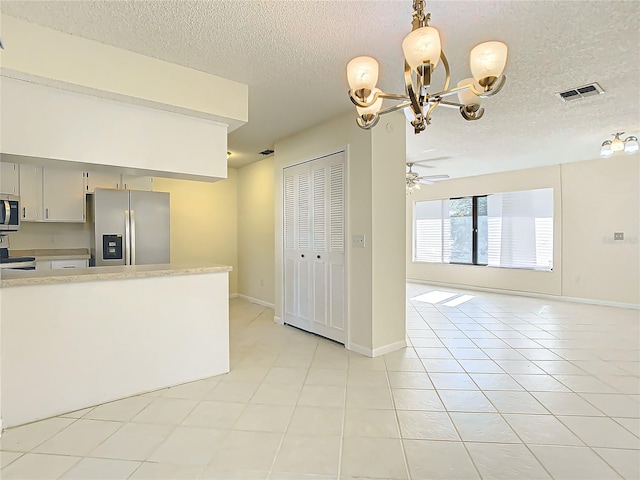 kitchen with hanging light fixtures, stainless steel appliances, a textured ceiling, light tile patterned floors, and ceiling fan with notable chandelier