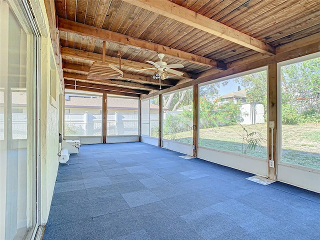 unfurnished sunroom with plenty of natural light, beamed ceiling, and wooden ceiling