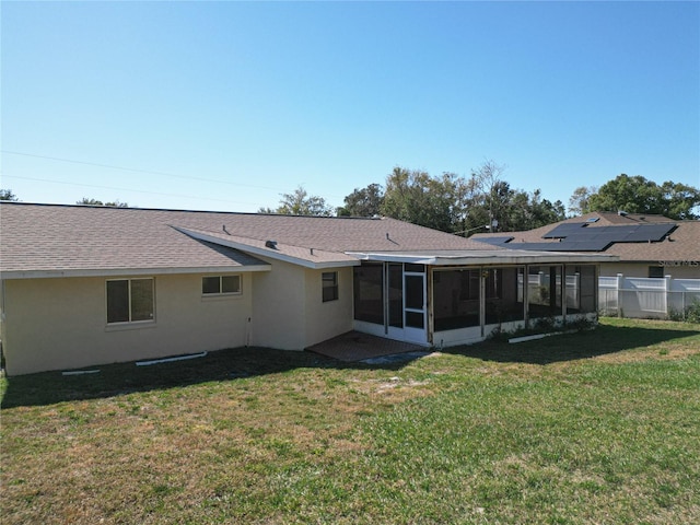 rear view of house featuring a yard and a sunroom