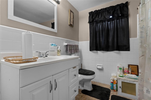 bathroom with vanity, toilet, and tile walls